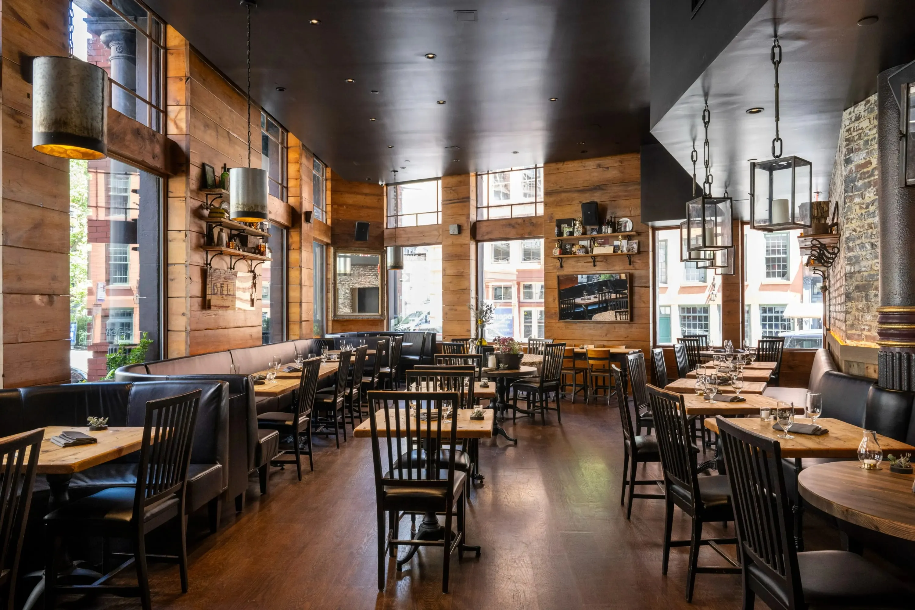 Dining room at Marc Forgione with exposed brick, timber-clad walls and warm pendant lighting