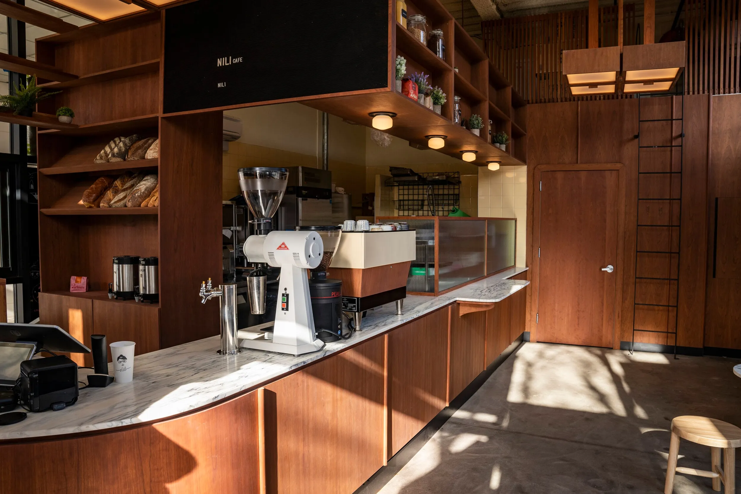 Walnut and marble counter at Nili with bread shelves and a ladder to upper storage
