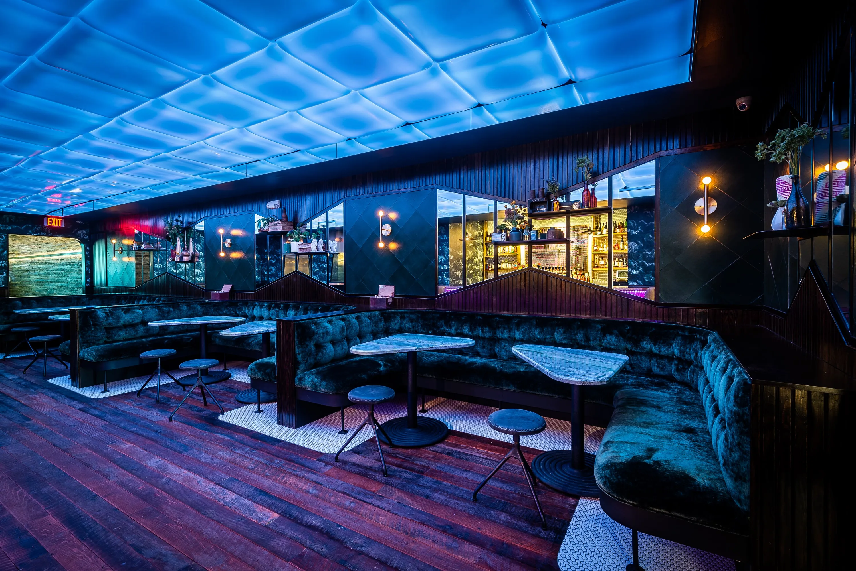 No Kisses interior under a full-ceiling illuminated grid, with velvet booths and the bar beyond
