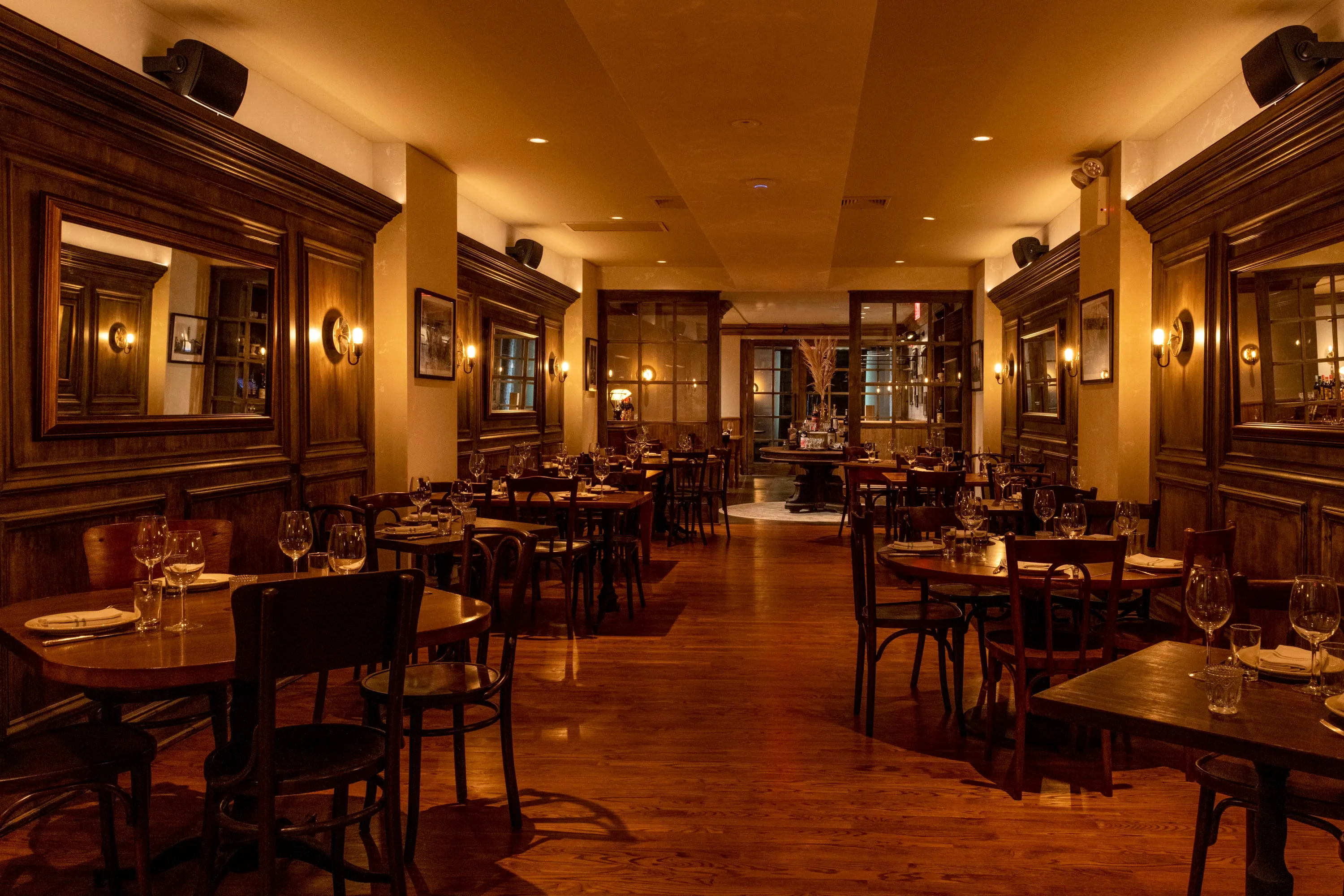 Main dining room at One Fifth with dark panelled walls, mirrors and wood tables