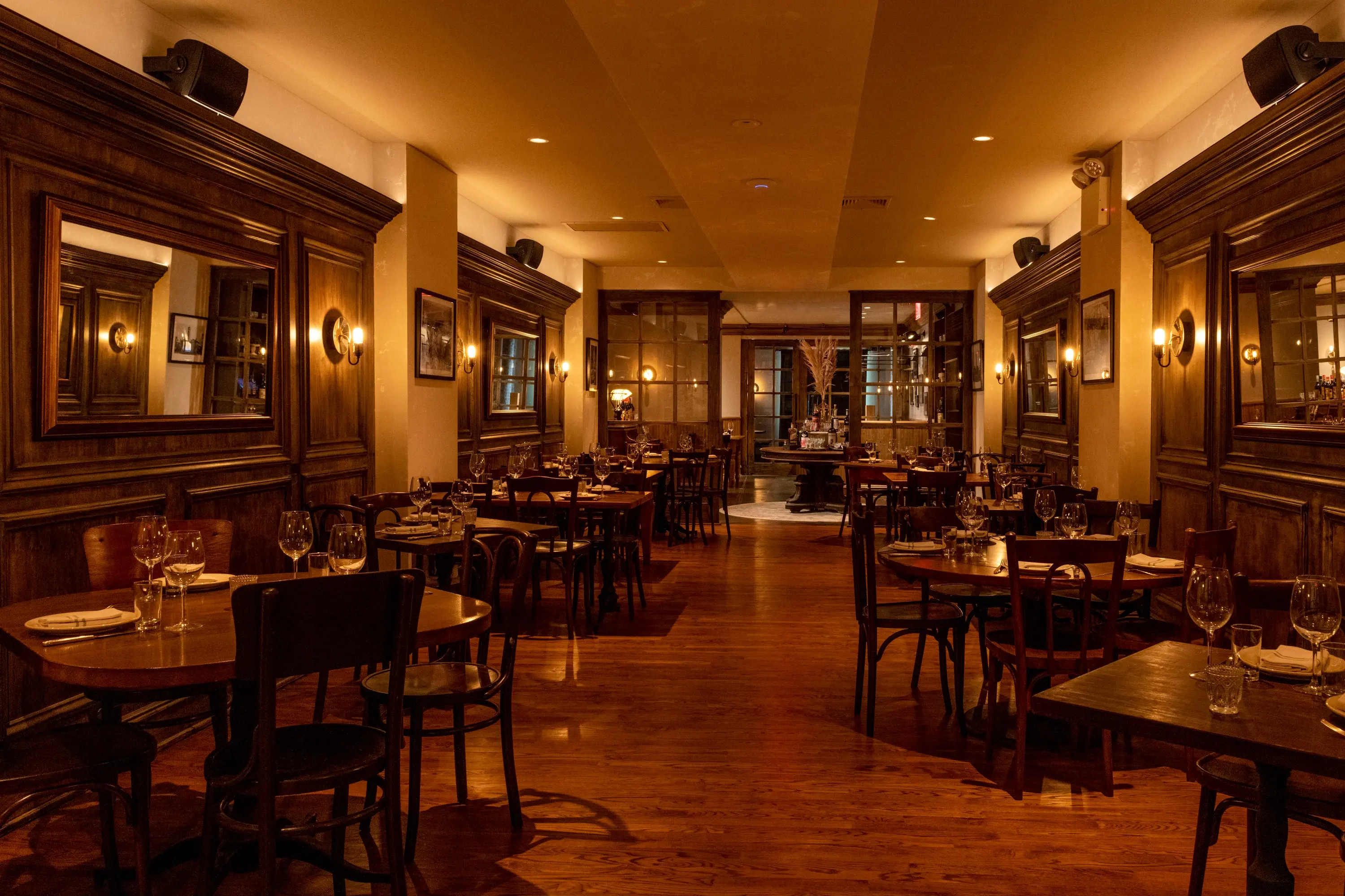 Main dining room at One Fifth with dark panelled walls, mirrors and wood tables