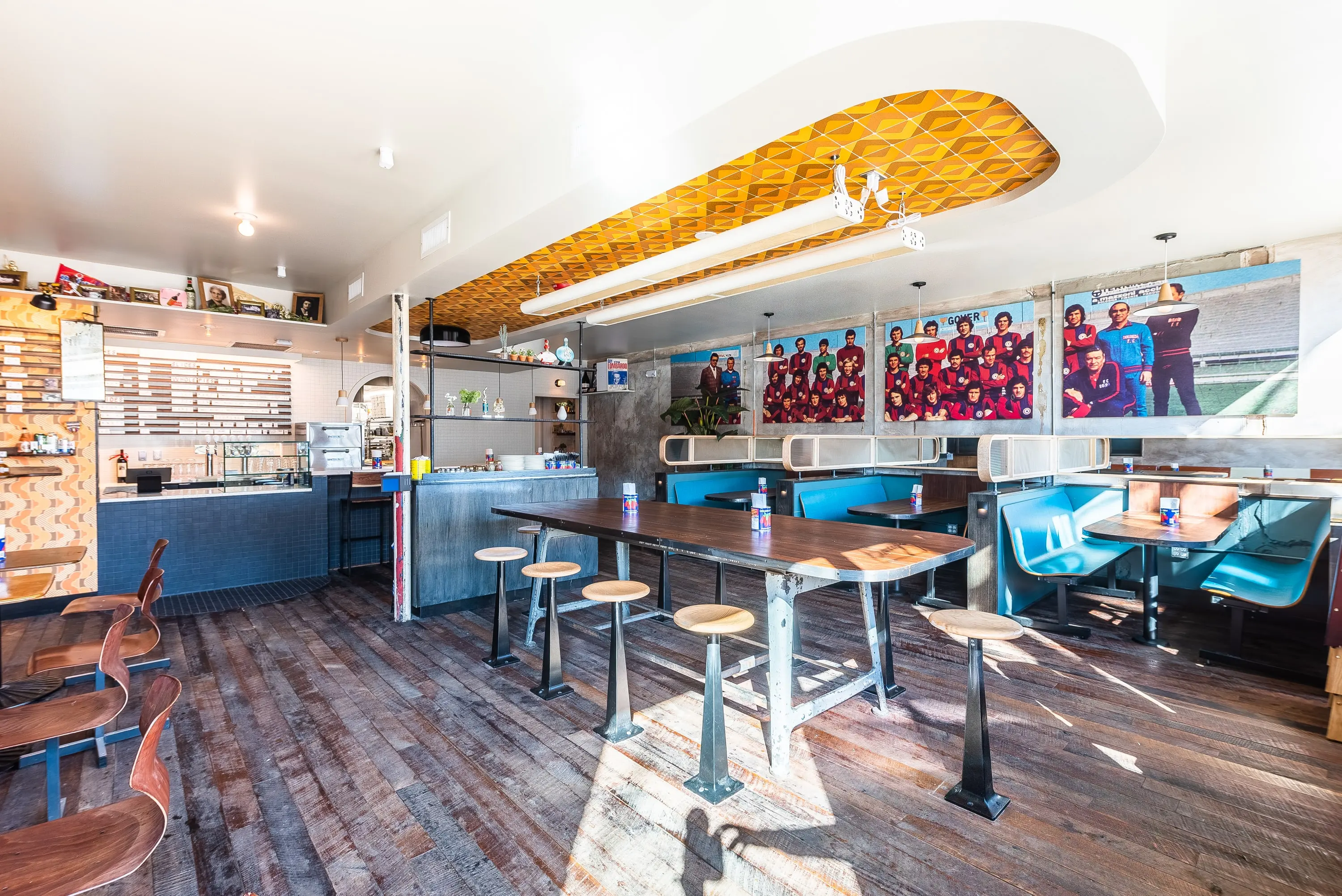 Sonny's Pizza dining room with teal booths, a patterned ceiling and framed photographs