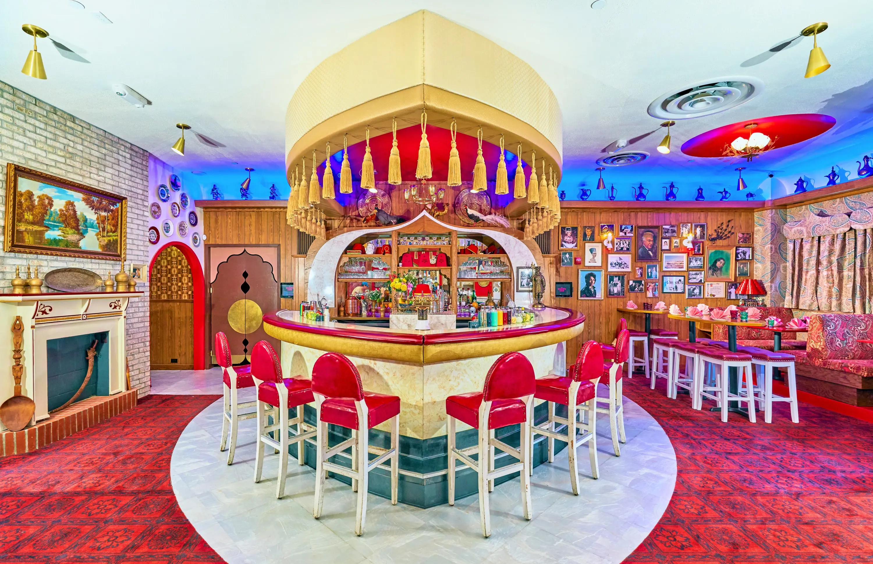 Turk's Inn dining room with a curved white bar, red stools and a canopy of decorative plates and lanterns