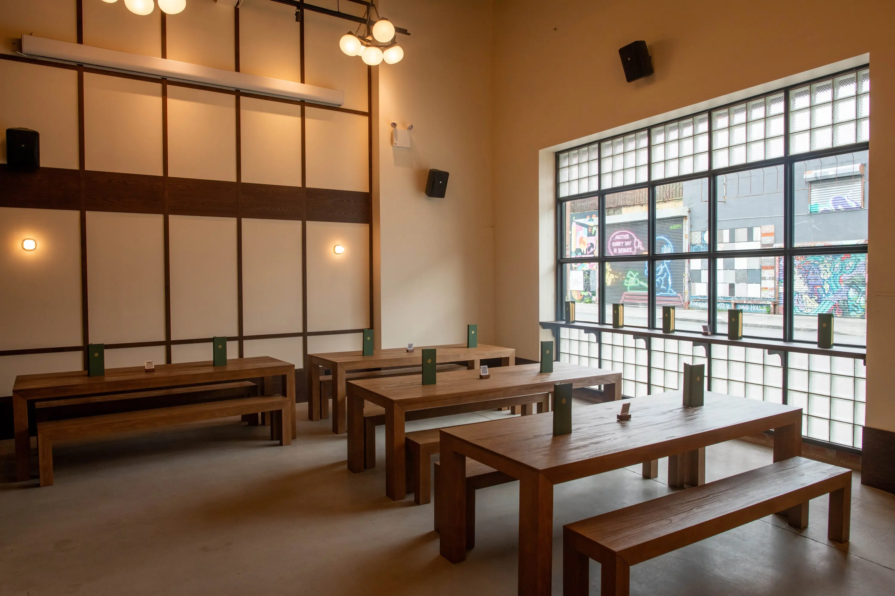 Communal oak tables in daylight beside gridded windows at Eckhart Beer Co