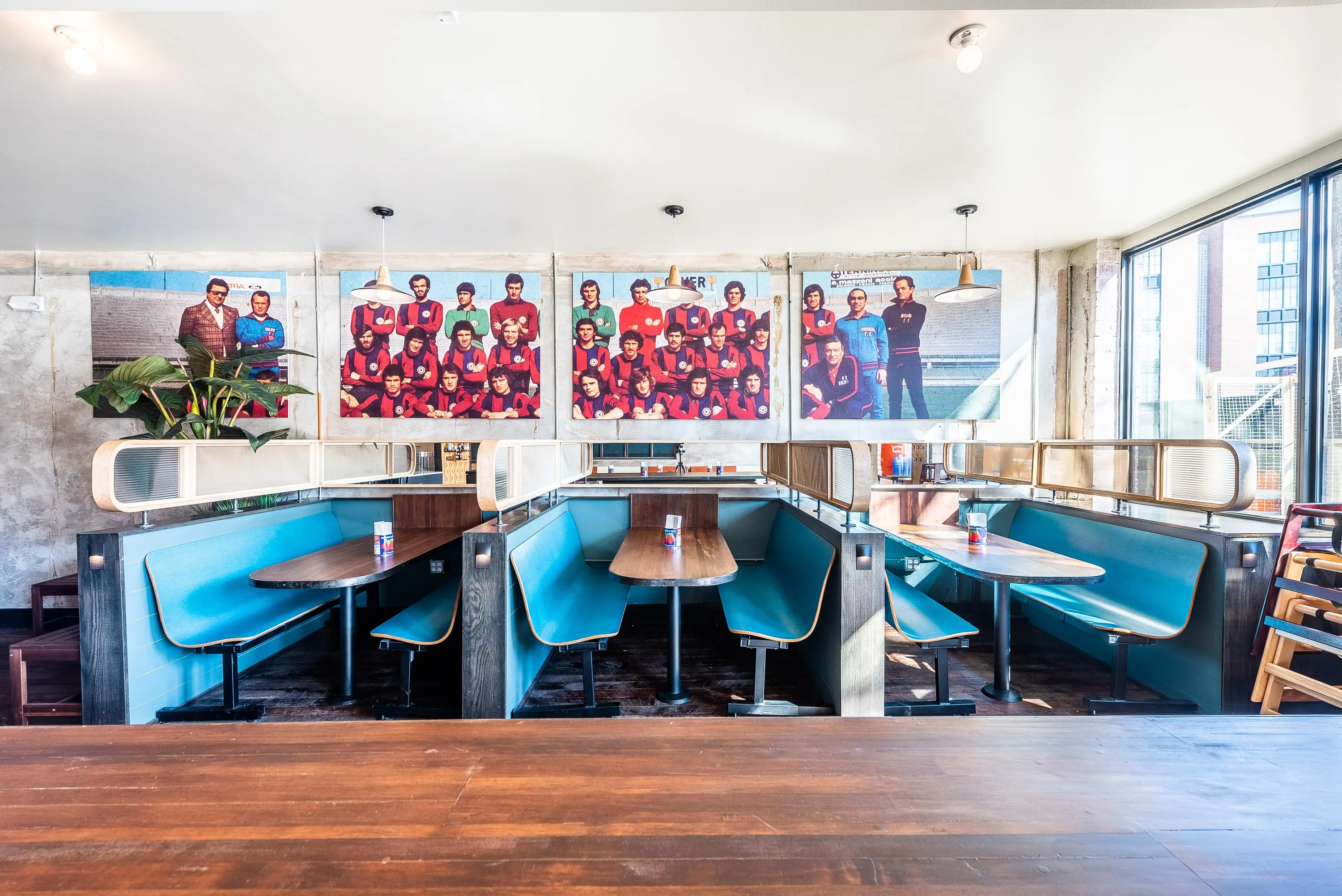 Teal booth seating at Sonny's Pizza beneath a row of framed team photographs