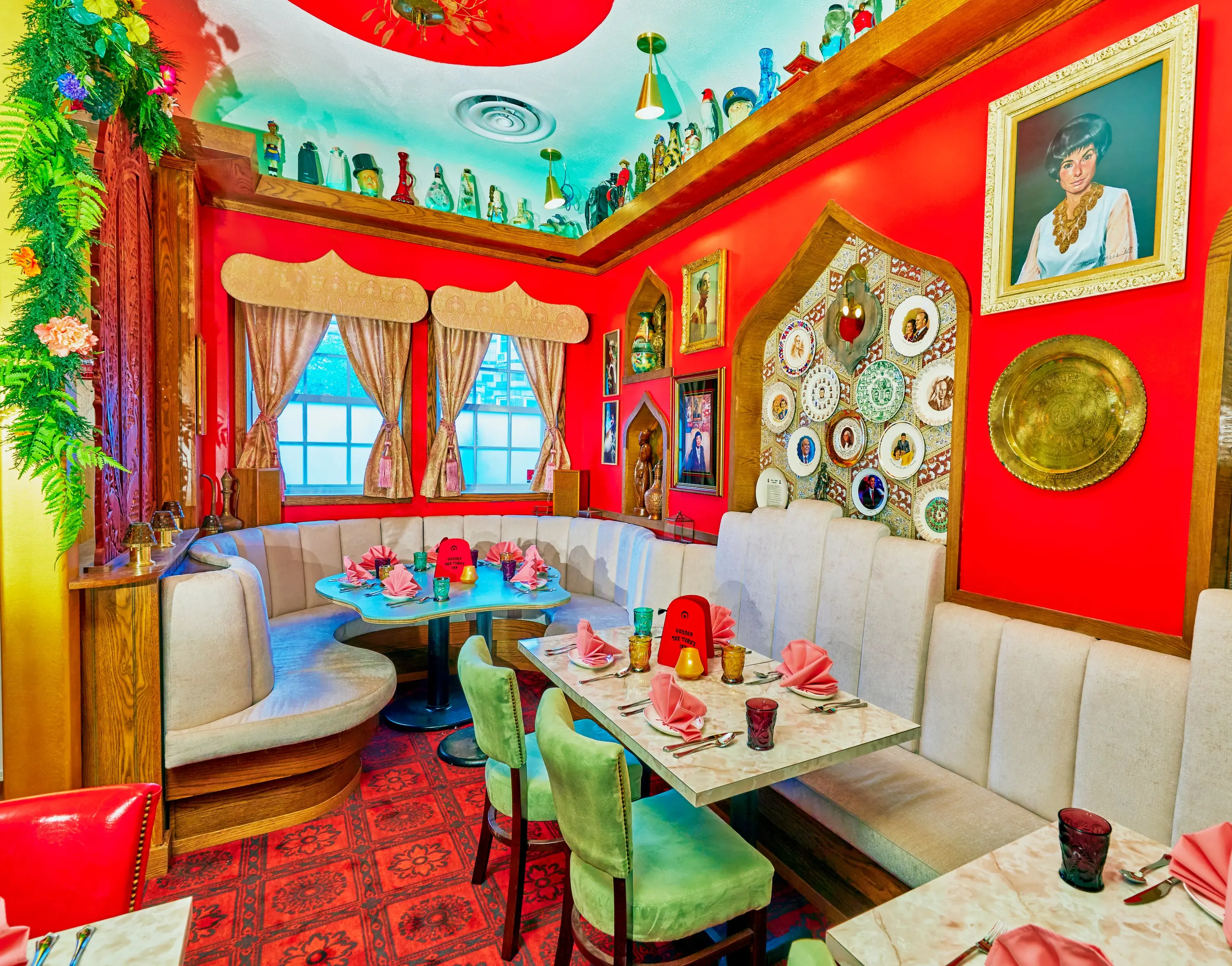 Corner booth at Turk's Inn against a red wall hung with brass plates and framed portraits