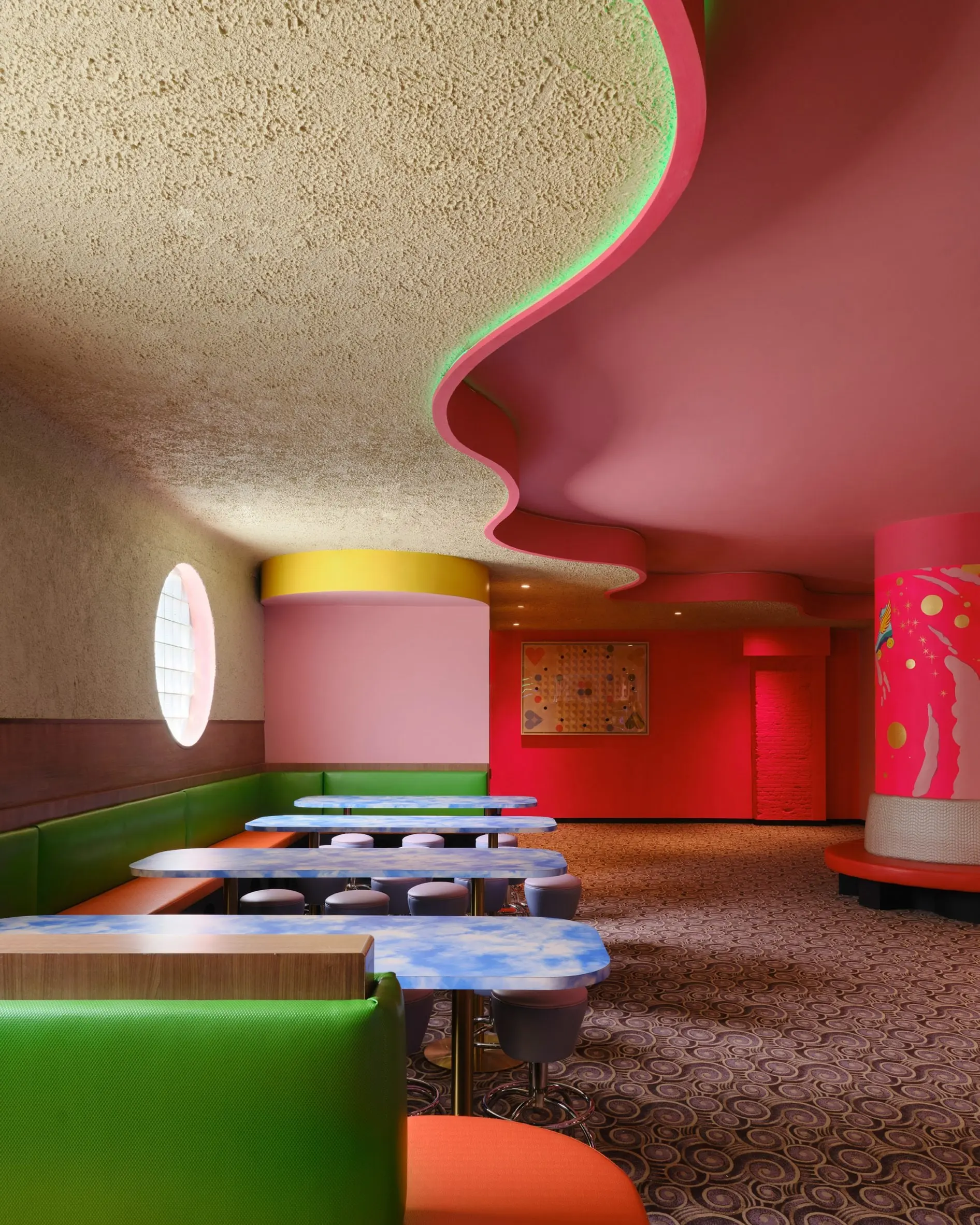 Lounge at Xanadu with a wave-form ceiling in pink and green and rounded banquettes