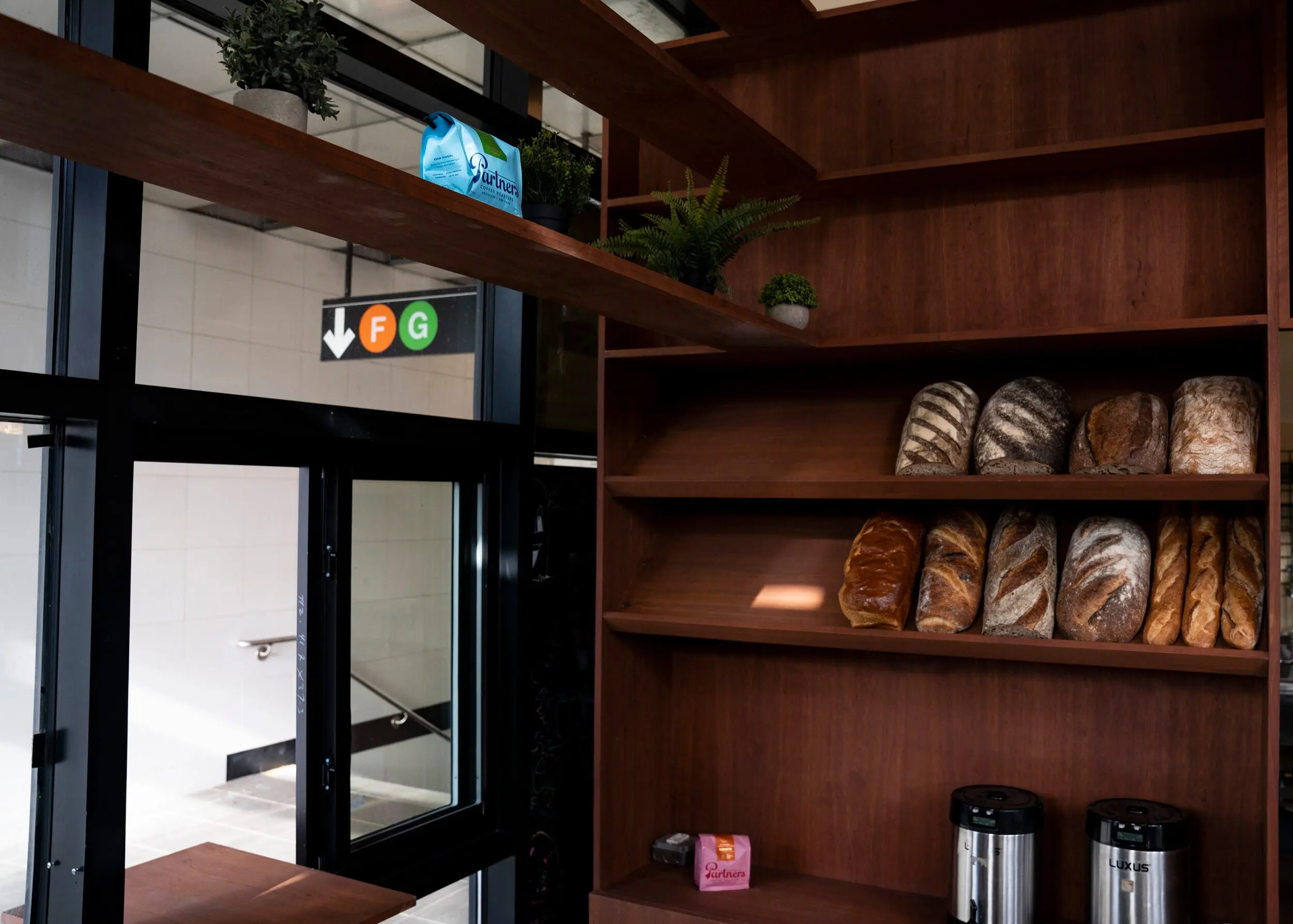 Open walnut shelving holding loaves of bread at Nili