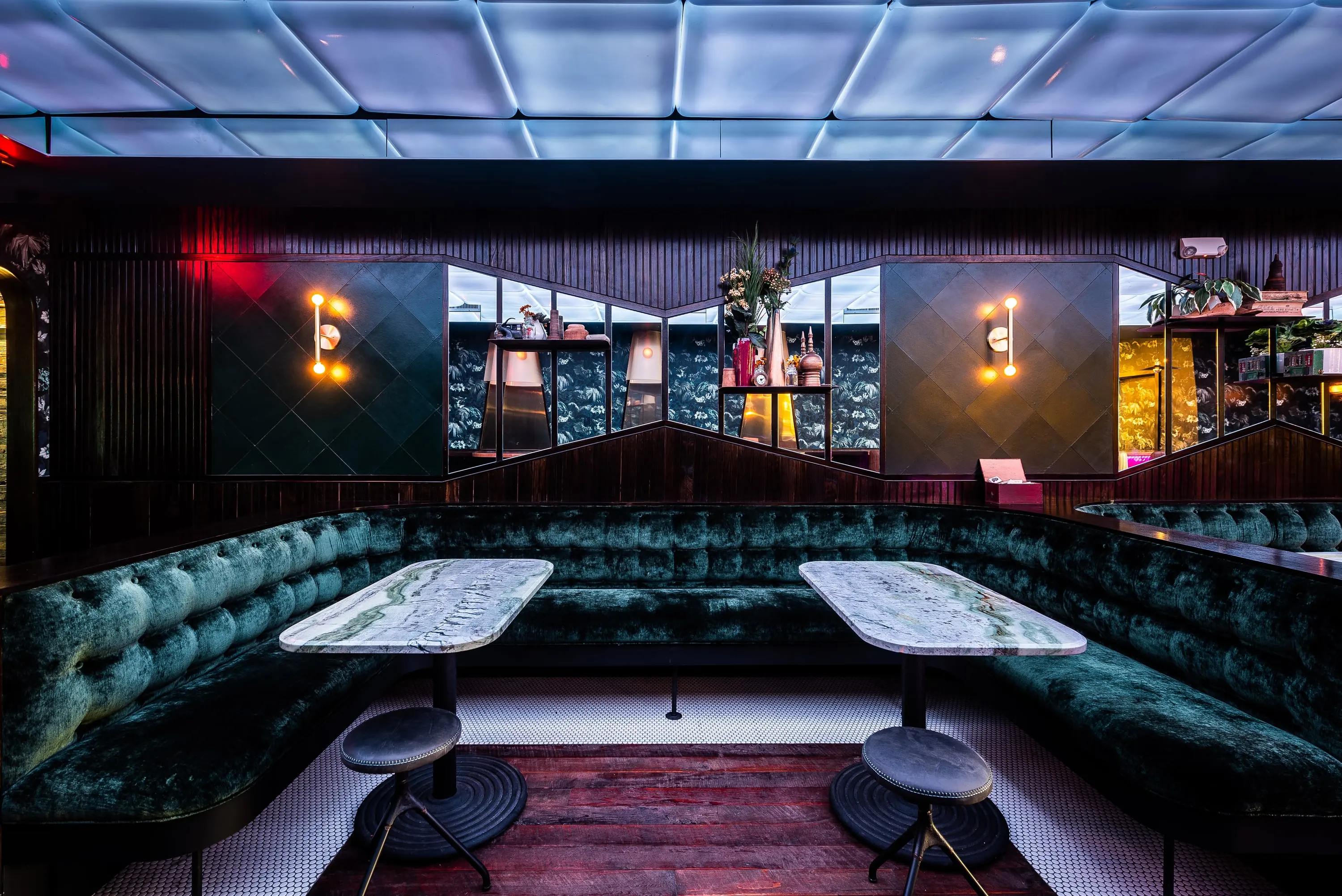 Green velvet booths at No Kisses beneath the illuminated ceiling