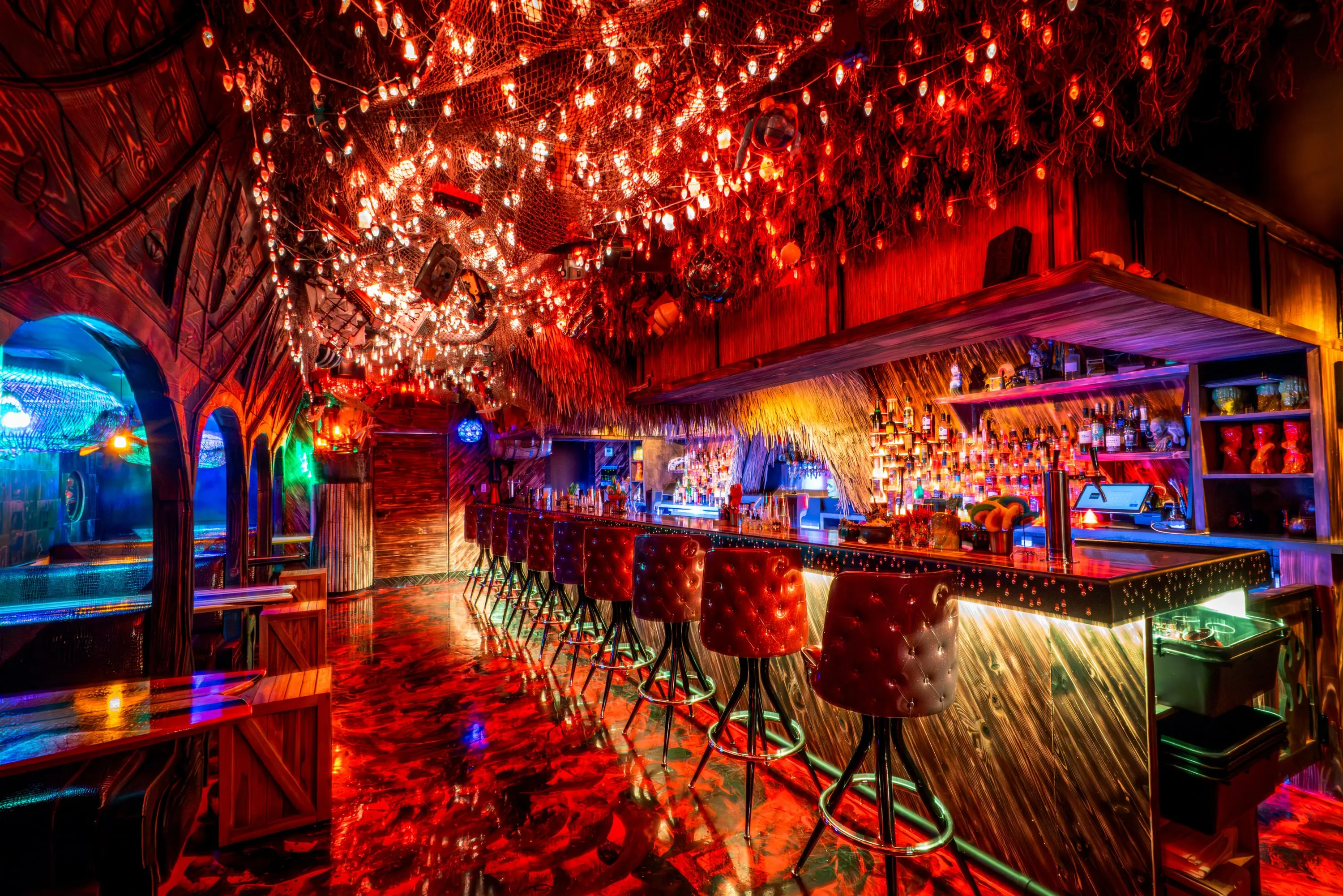 Paradise Lost bar bathed in red light beneath a sculpted ceiling of branches and blossoms