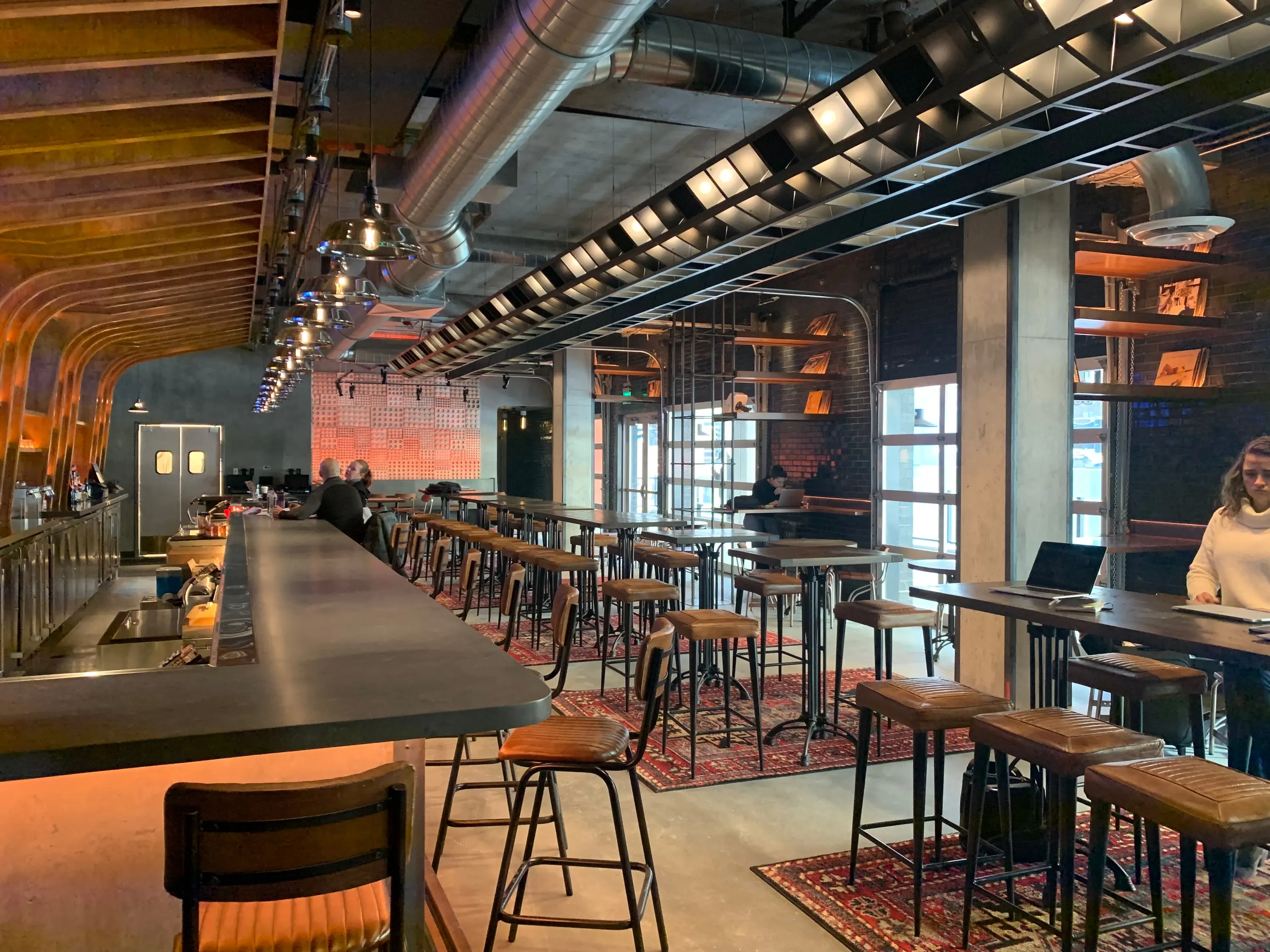 Wide view of Trax with high tables, rugs and the record wall behind the bar