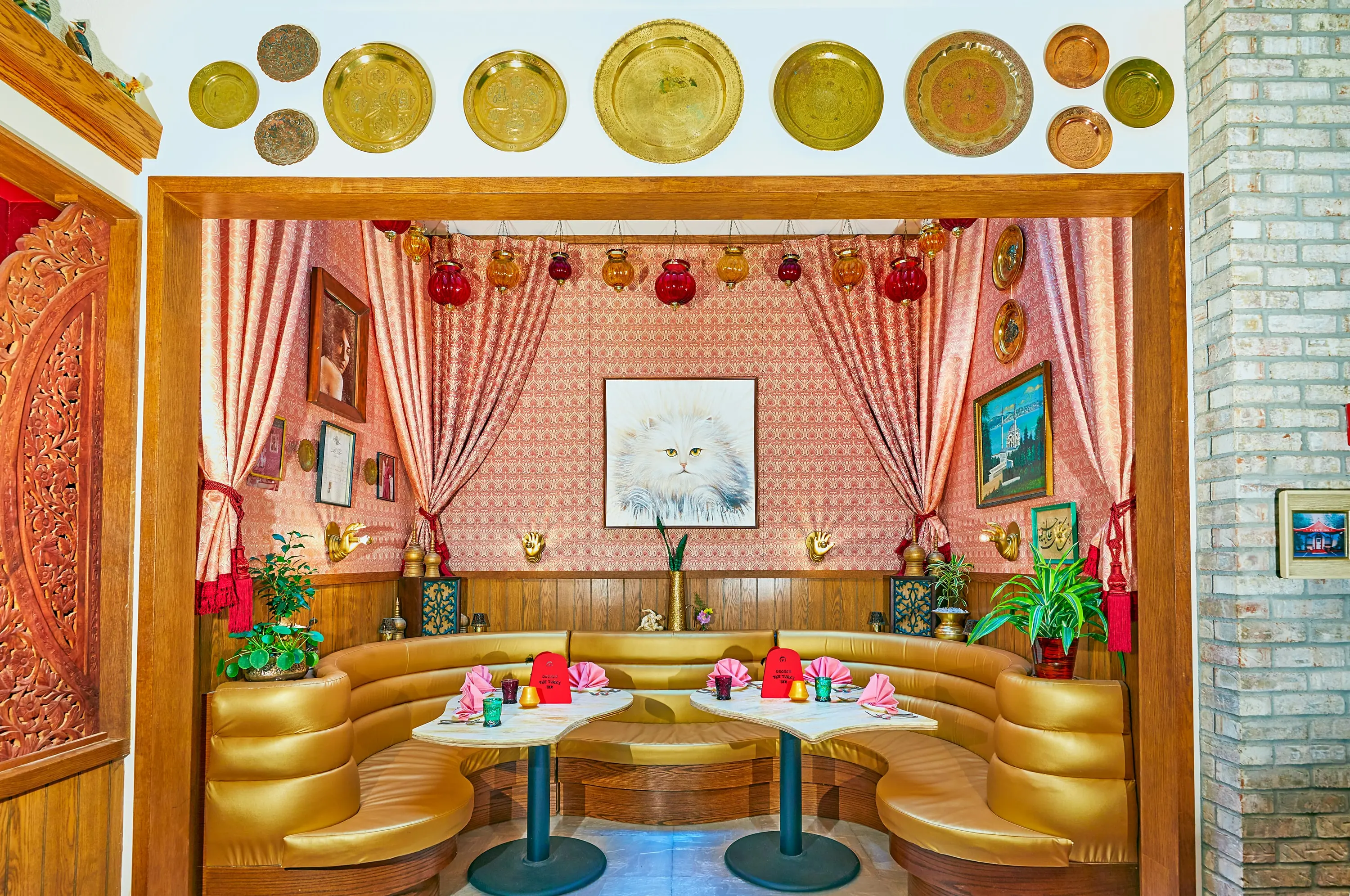 Cream leather booth at Turk's Inn beneath a large framed portrait of a white cat