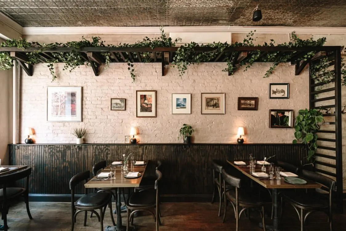 Banquette wall at Clover Hill with a row of small framed pictures and wall sconces