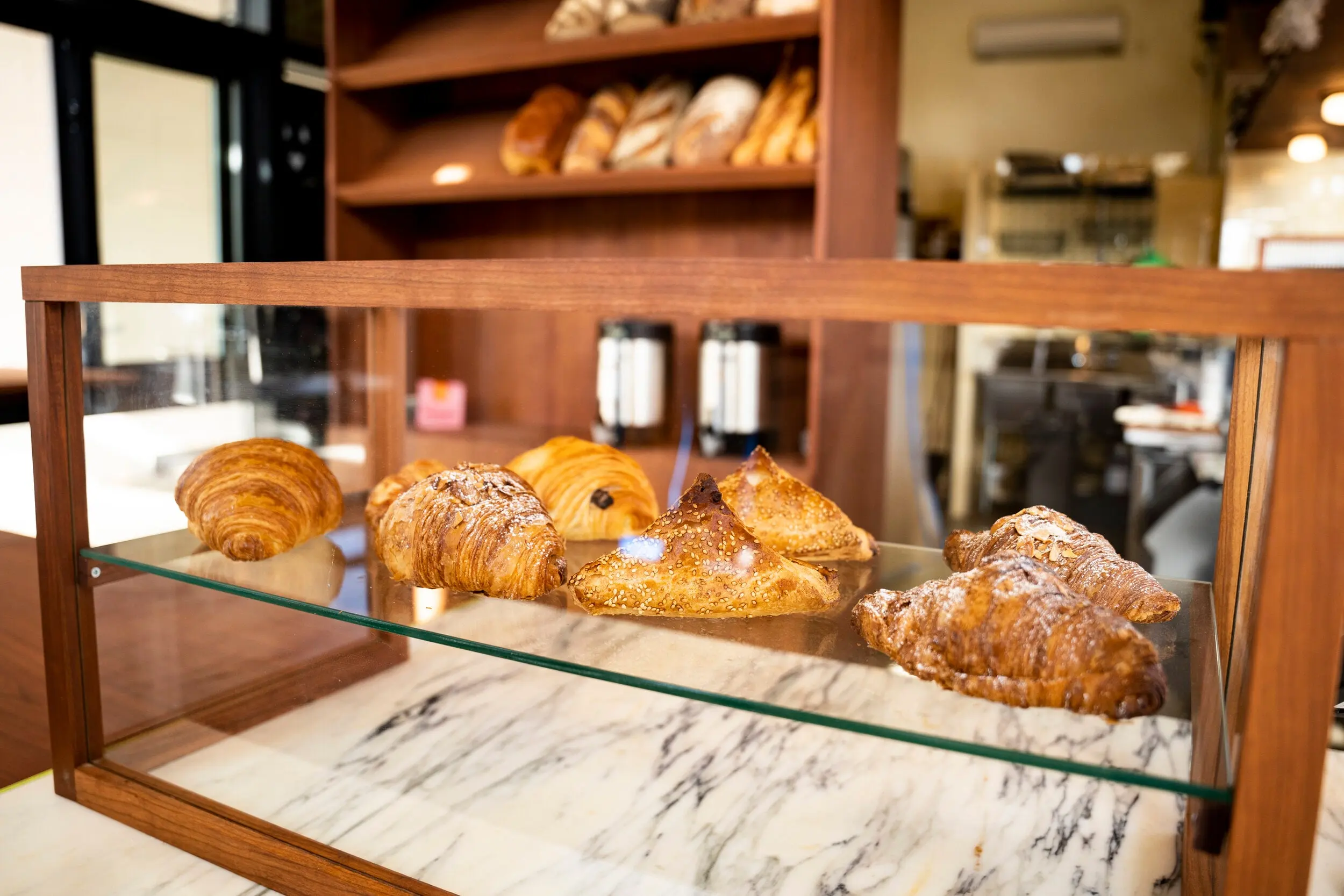 Glass pastry case with croissants on the marble counter at Nili
