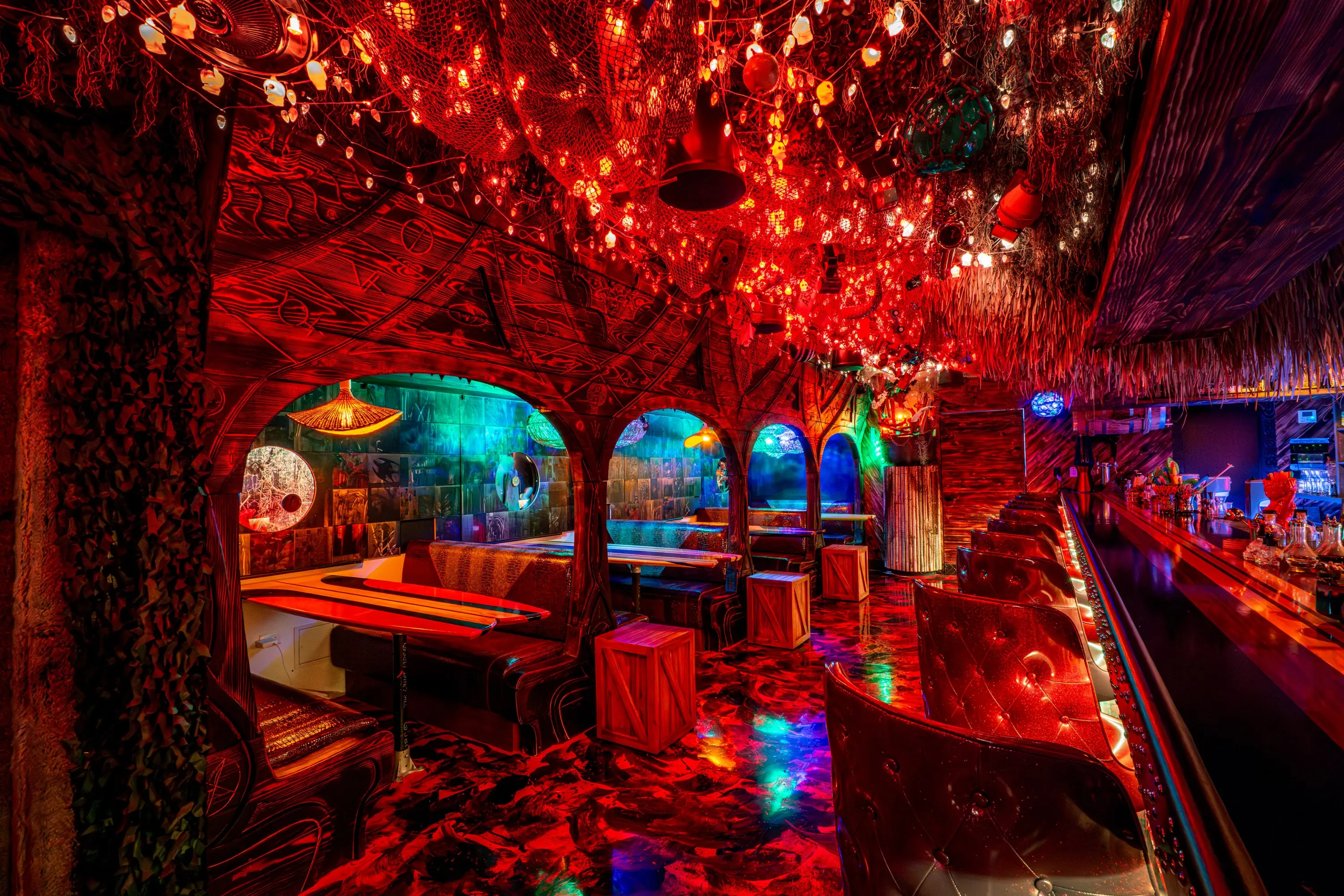Booth seating at Paradise Lost beneath a red-lit tree canopy with lanterns