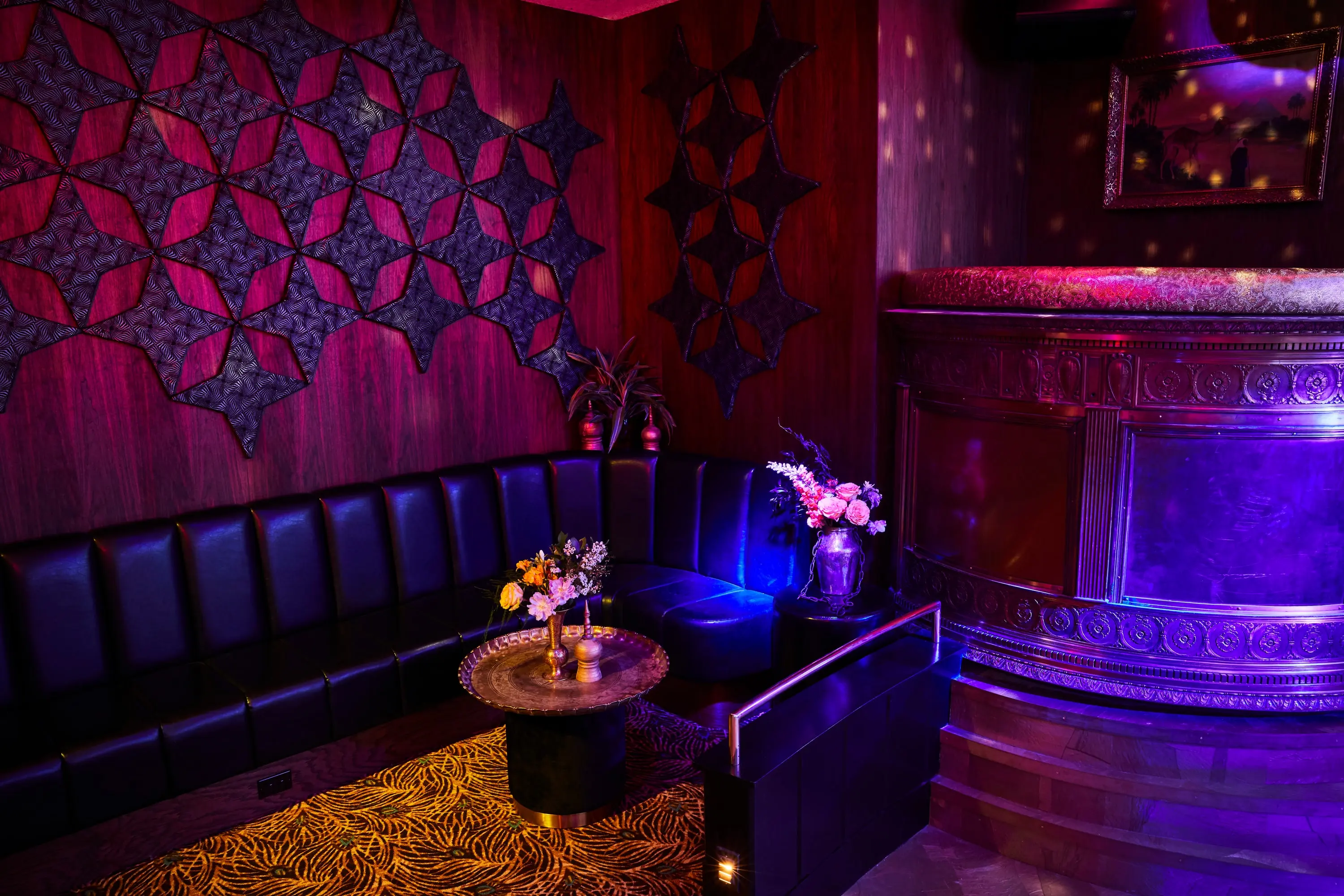 VIP lounge at The Sultan Room with a leather banquette beneath carved wall panels