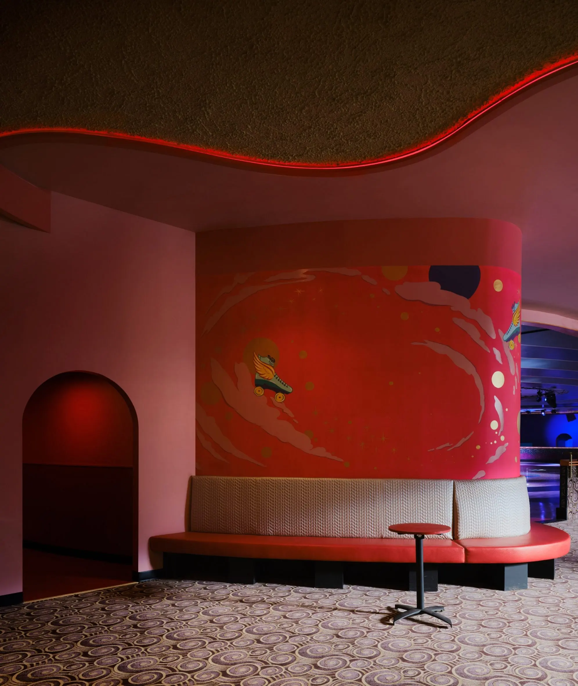 Curved banquette beneath a red mural of a skater at Xanadu