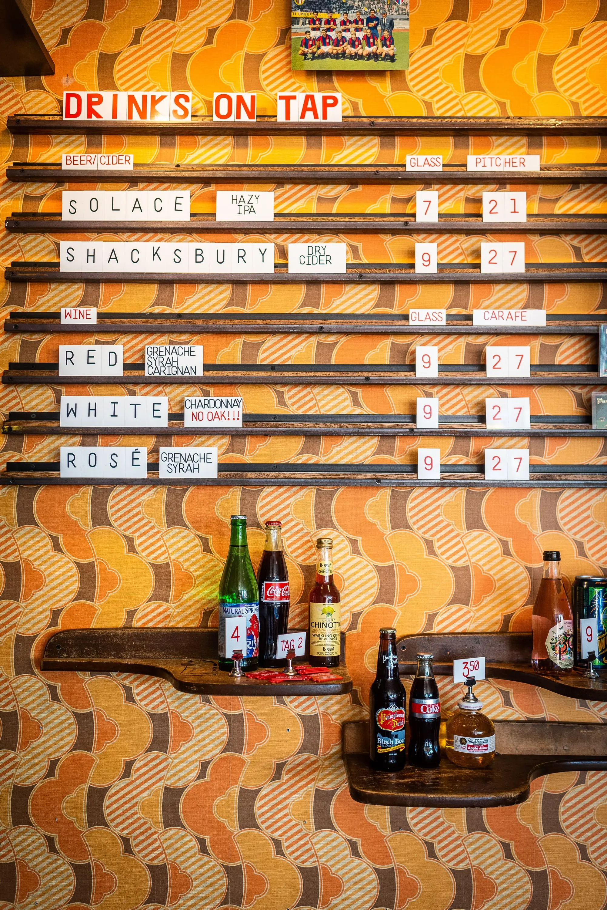 Letterboard drinks menu against patterned orange wallpaper at Sonny's Pizza