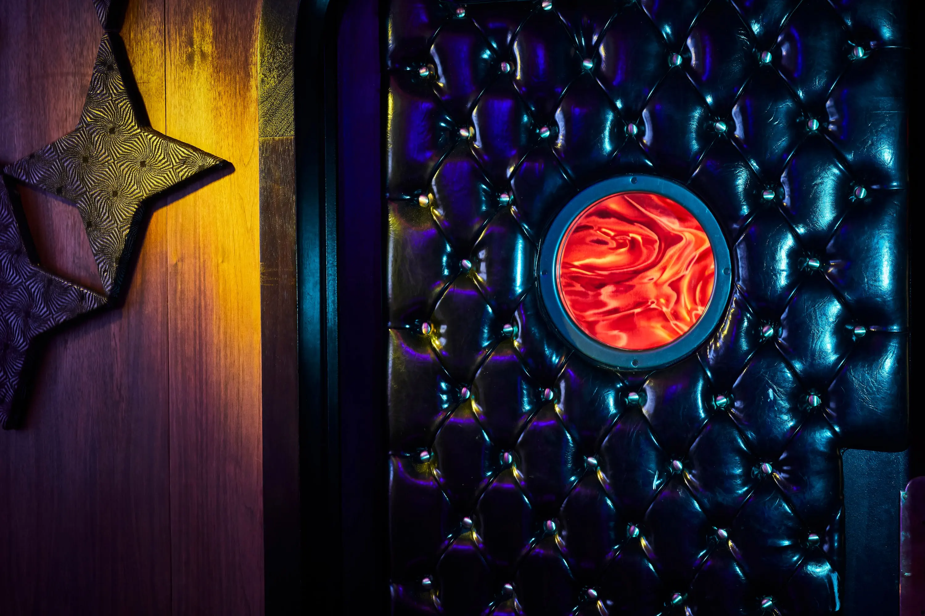 Tufted black leather door with a porthole window at The Sultan Room