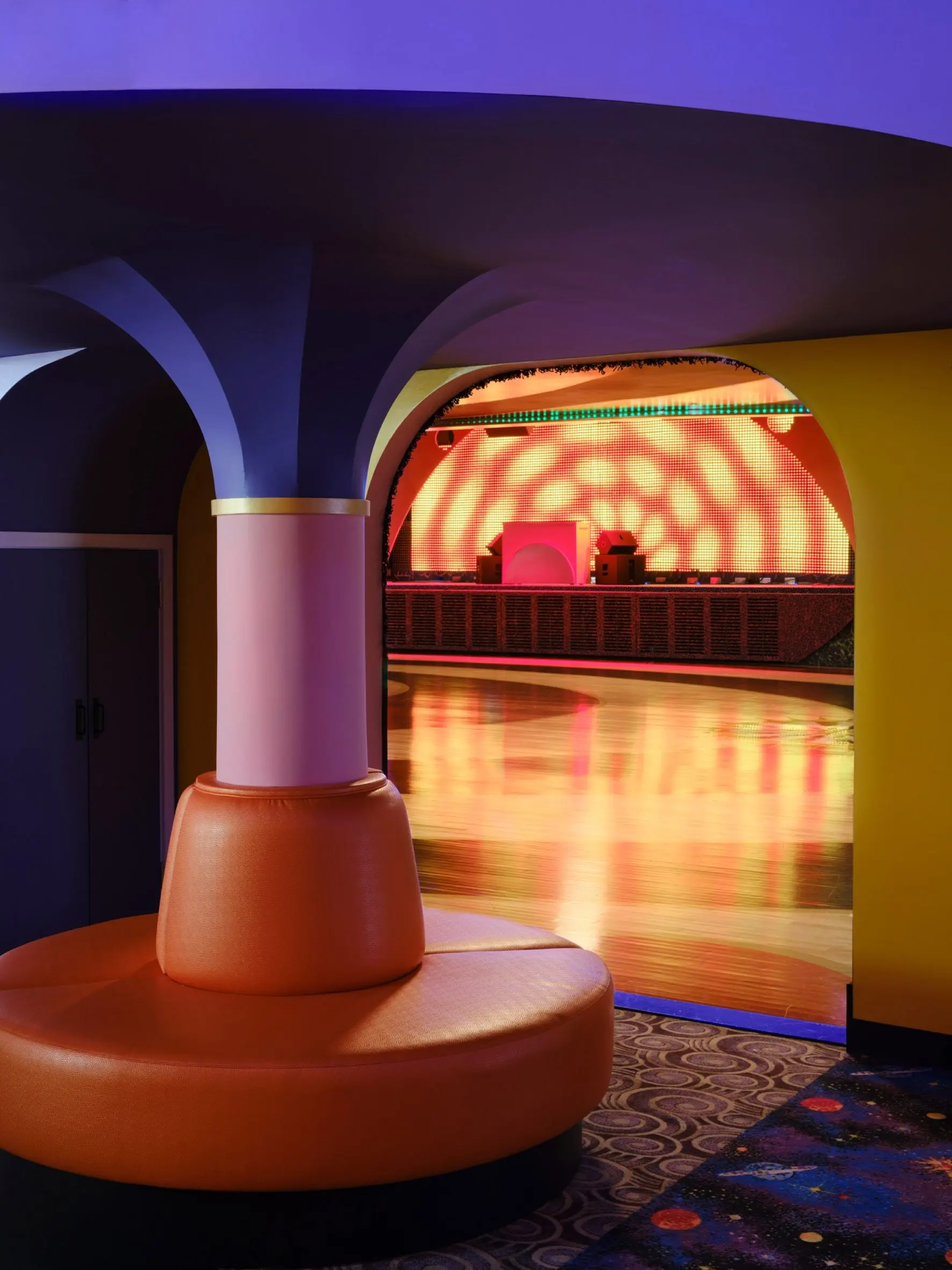 Rounded padded seat wrapping a column at Xanadu with the rink beyond