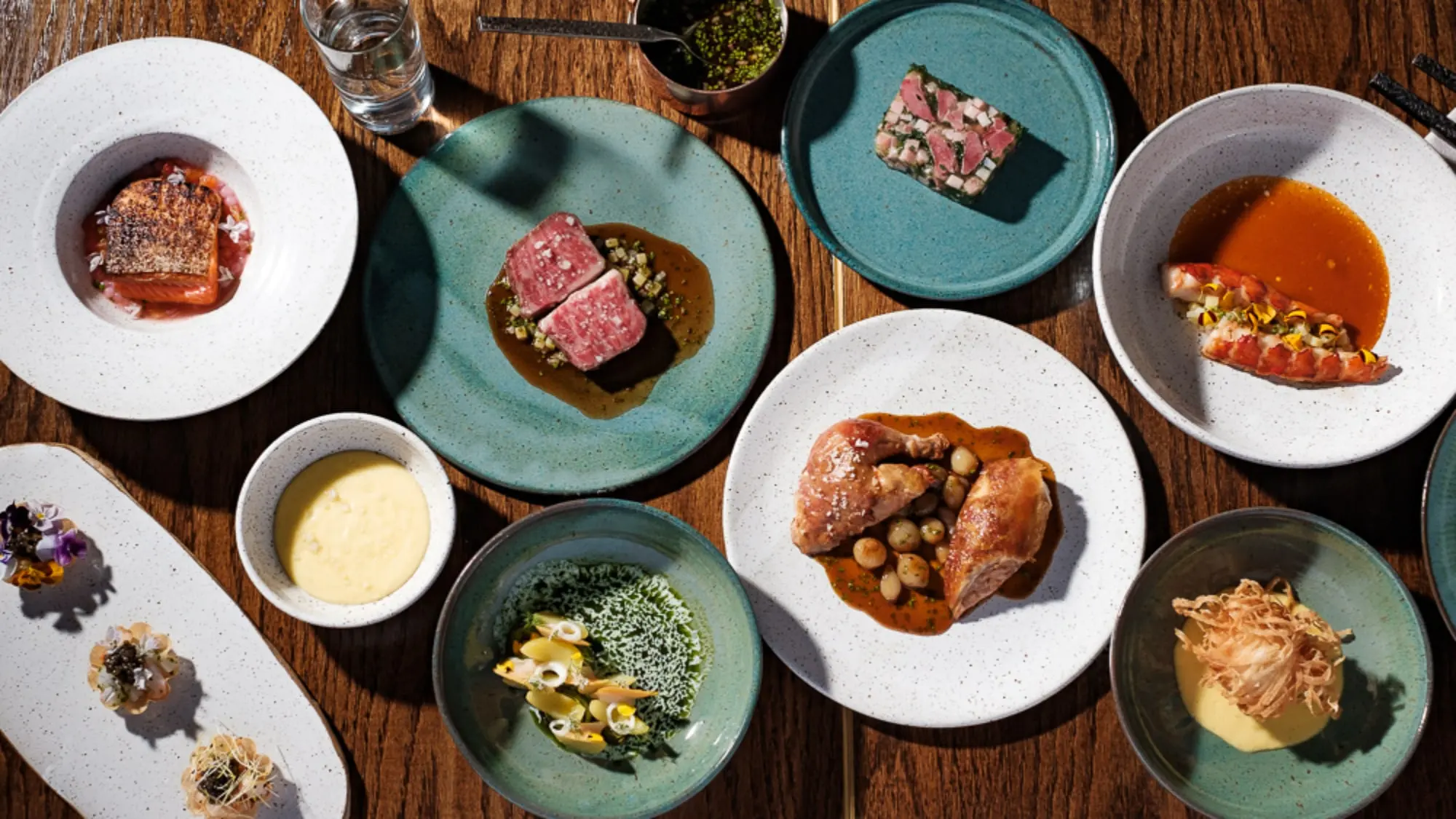 Tasting-menu courses plated on green and white ceramics at Clover Hill