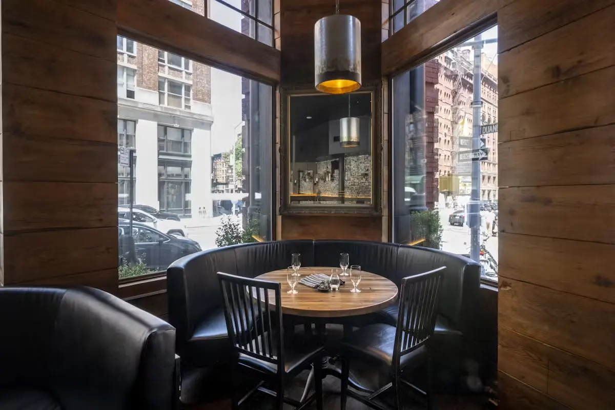Corner booth at Marc Forgione beside tall windows