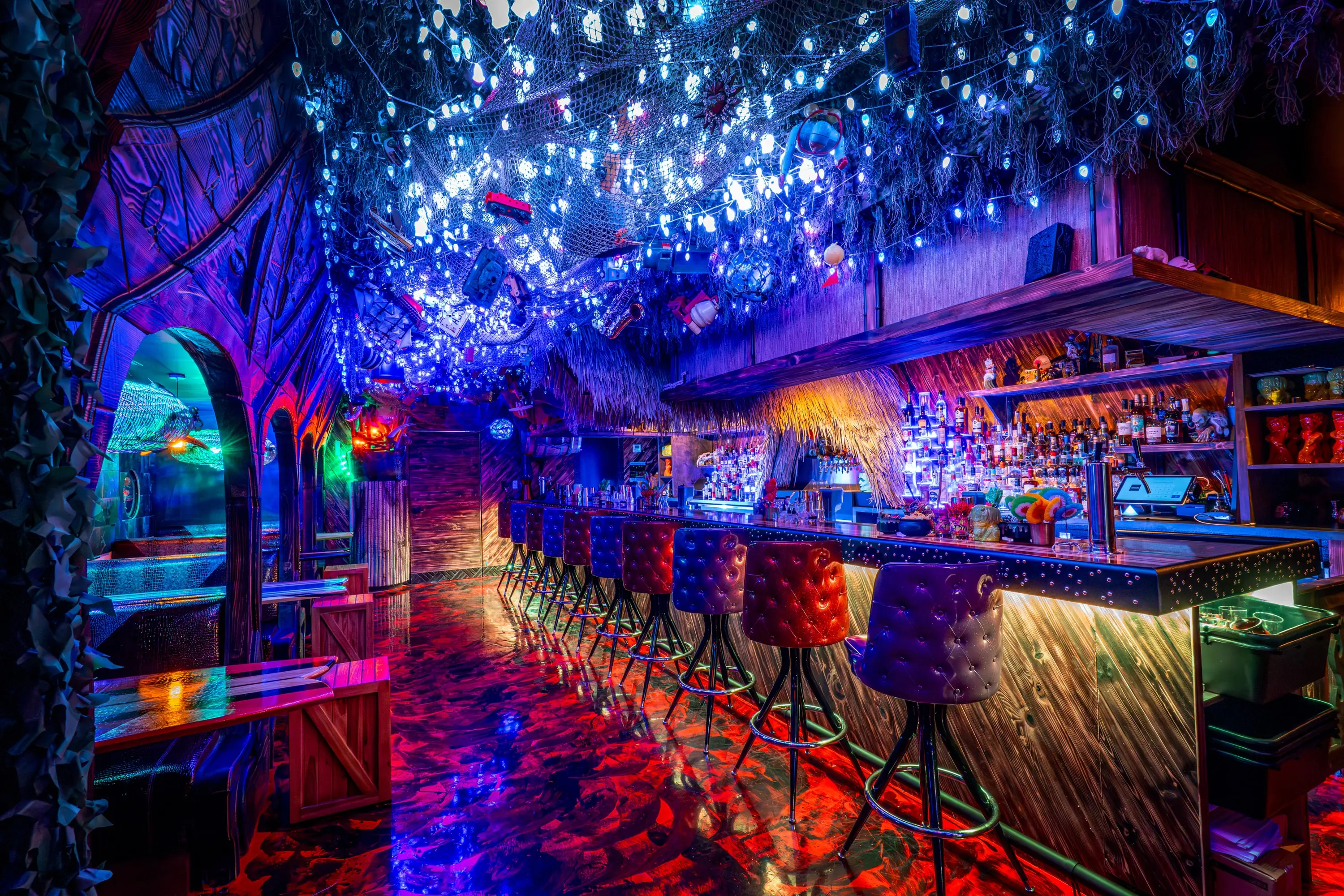 Long view down the Paradise Lost bar in blue light with a red-glowing floor