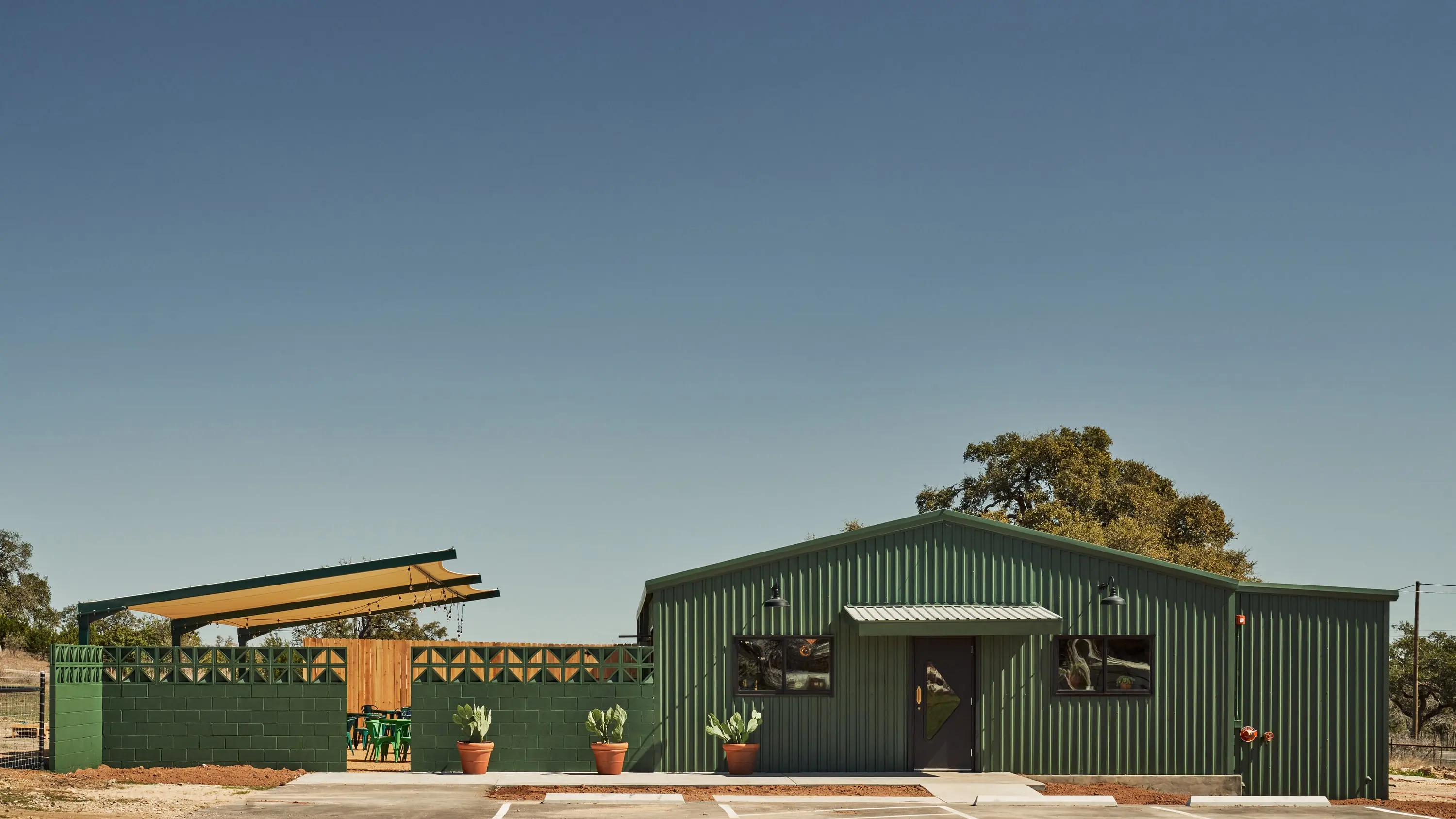 Green metal building housing the Senza Maeso tasting room under a clear sky