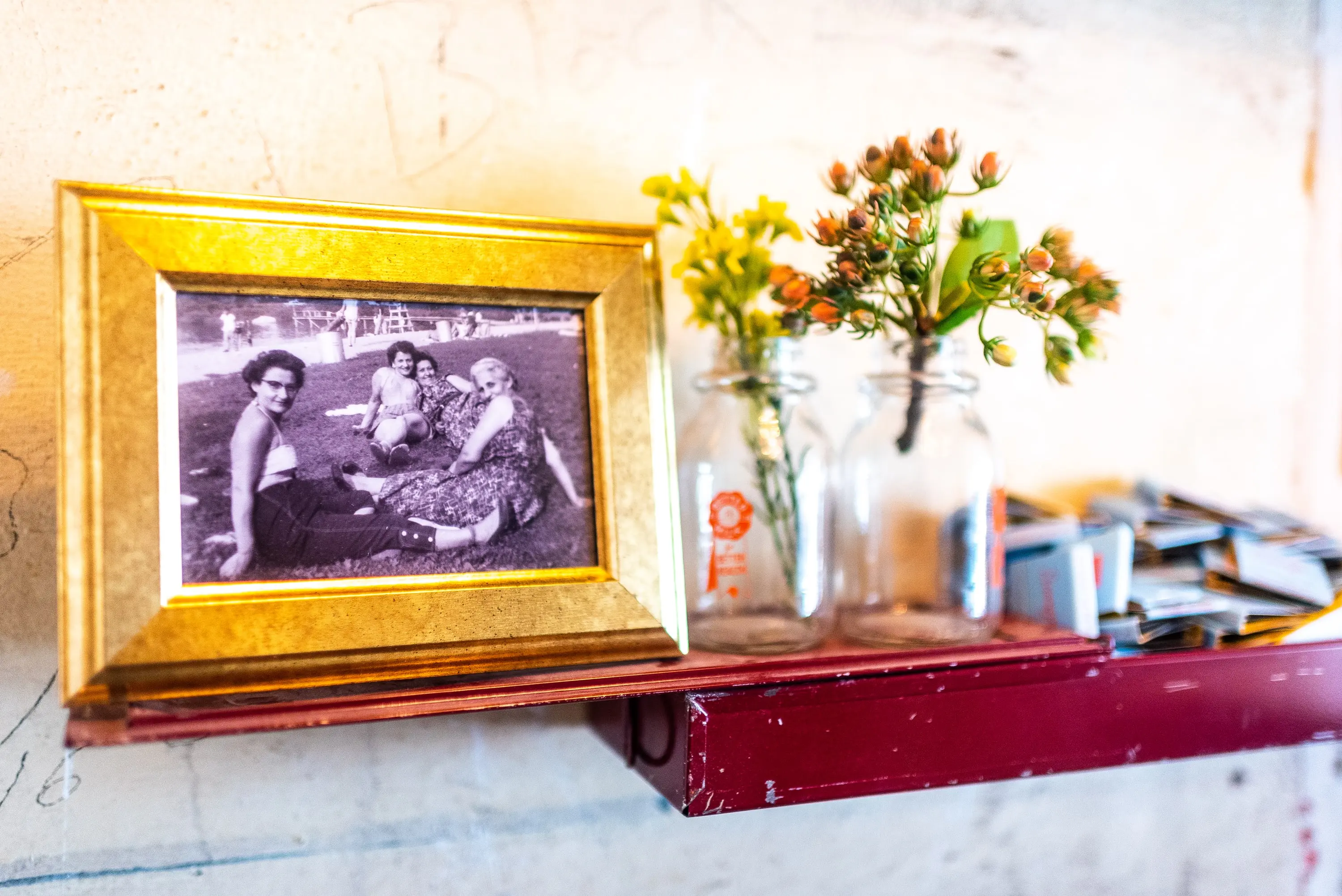 Gold-framed photograph and flowers on a red shelf at Sonny's Pizza