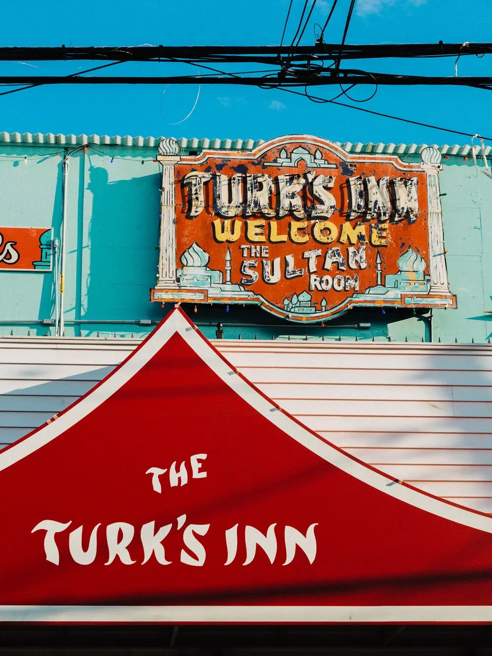 The original Turk's Inn sign mounted above the red roofline against a blue sky