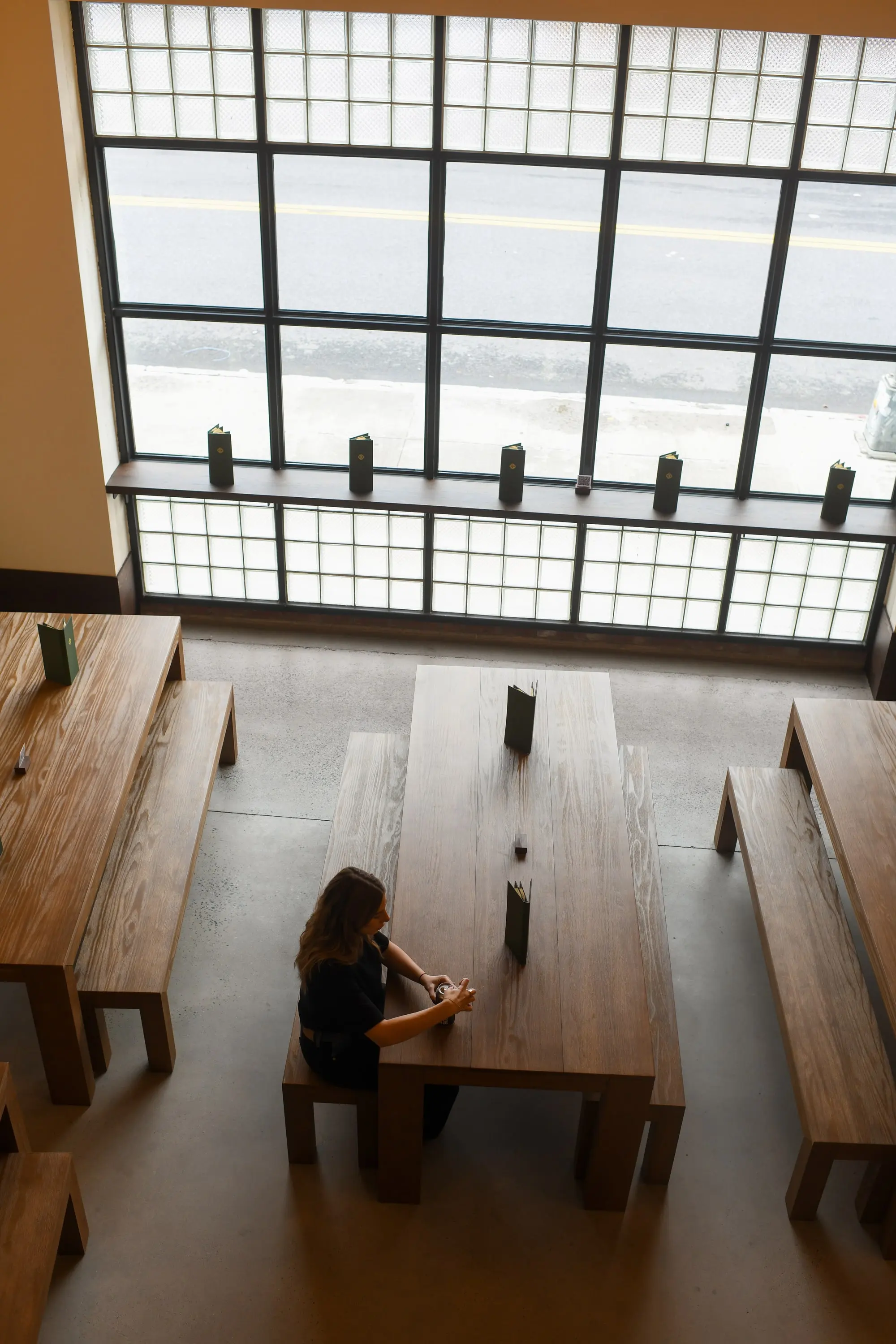 Tall gridded window and communal table at Eckhart Beer Co, seen from the mezzanine