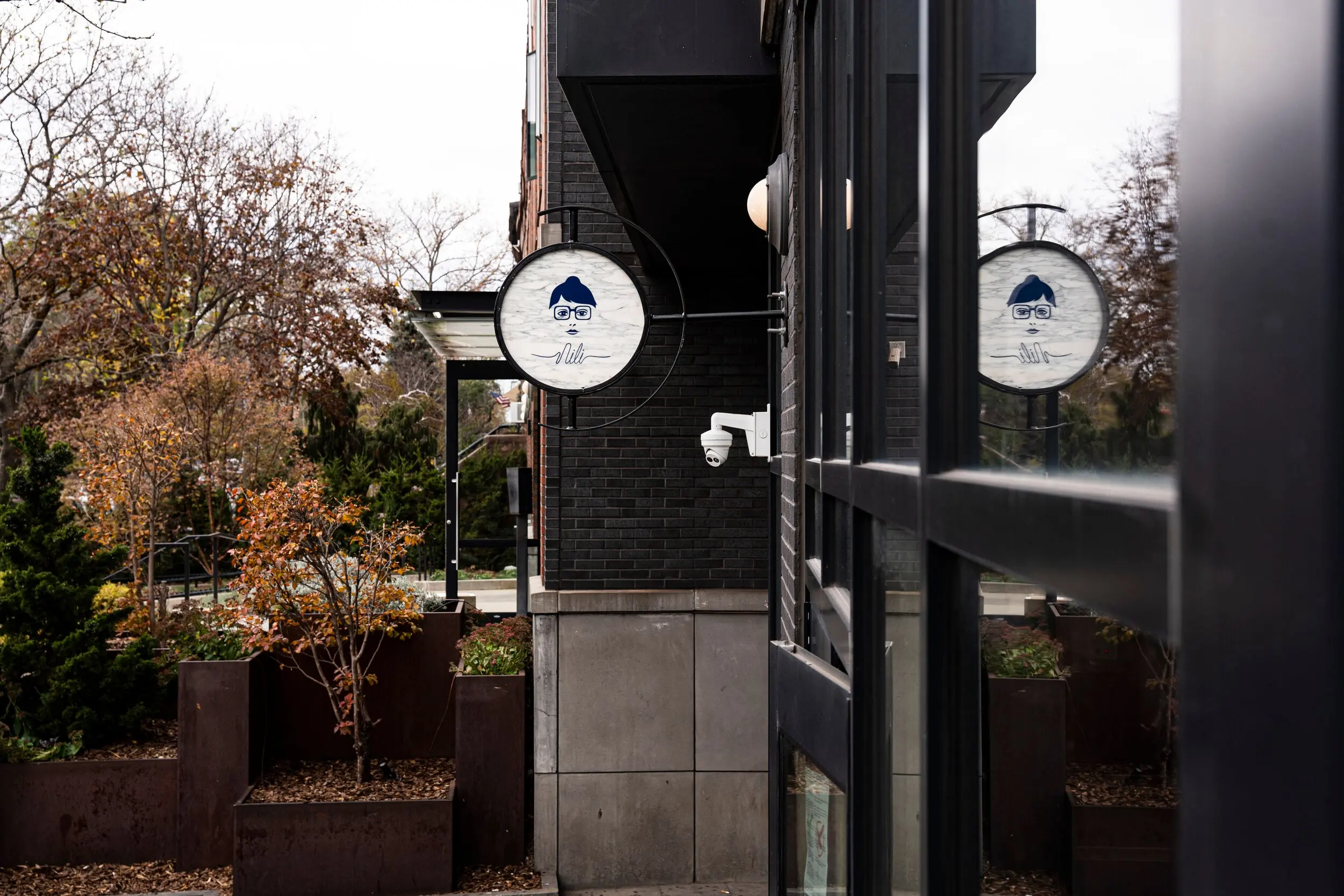 Round Nili signs projecting from the shopfront on a Carroll Gardens corner