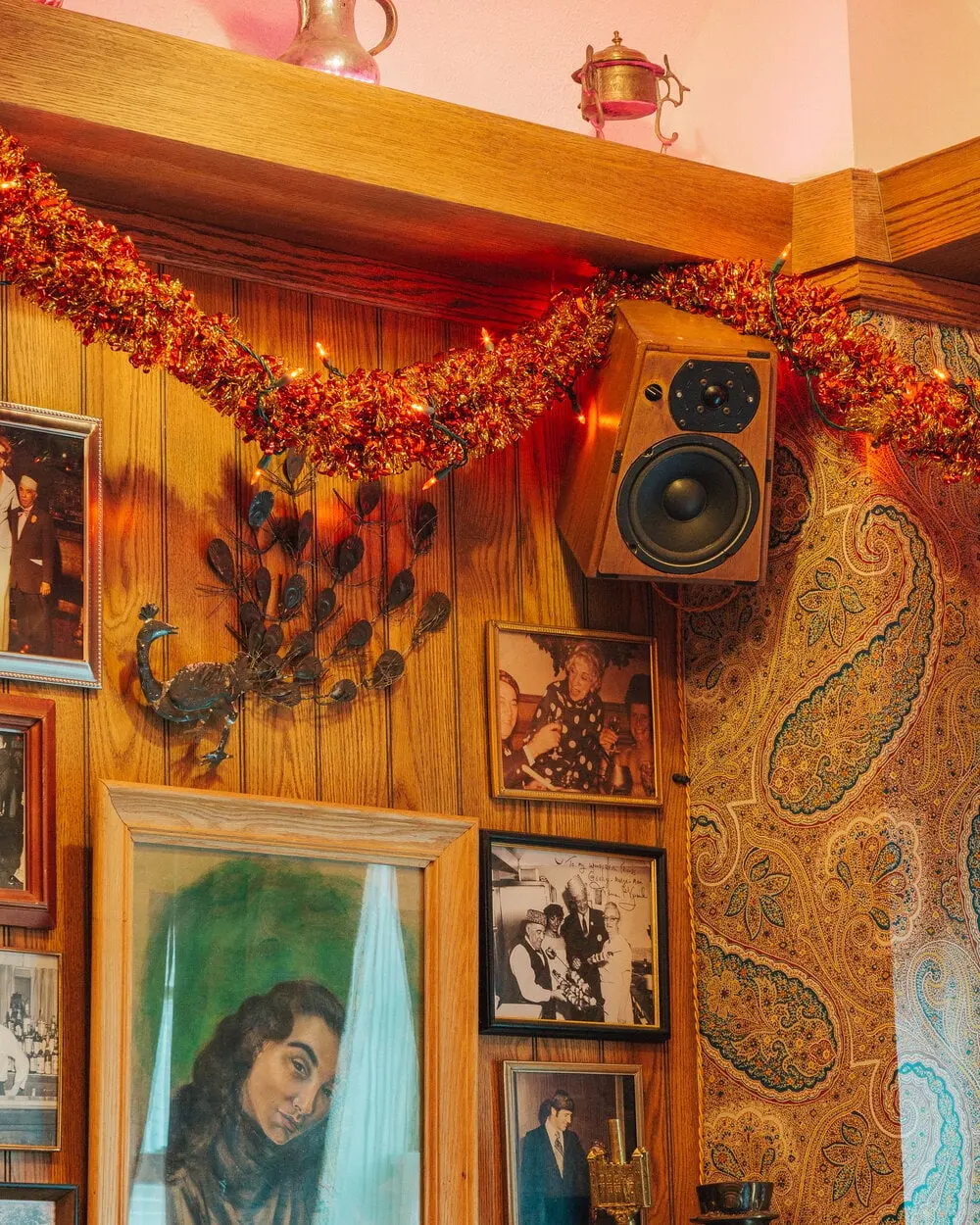 Vintage speaker, framed portraits and garland against paisley wallpaper at Turk's Inn