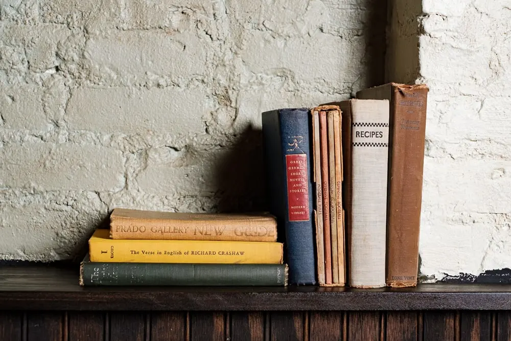 Stack of cookbooks on a shelf against a whitewashed brick wall at Clover Hill