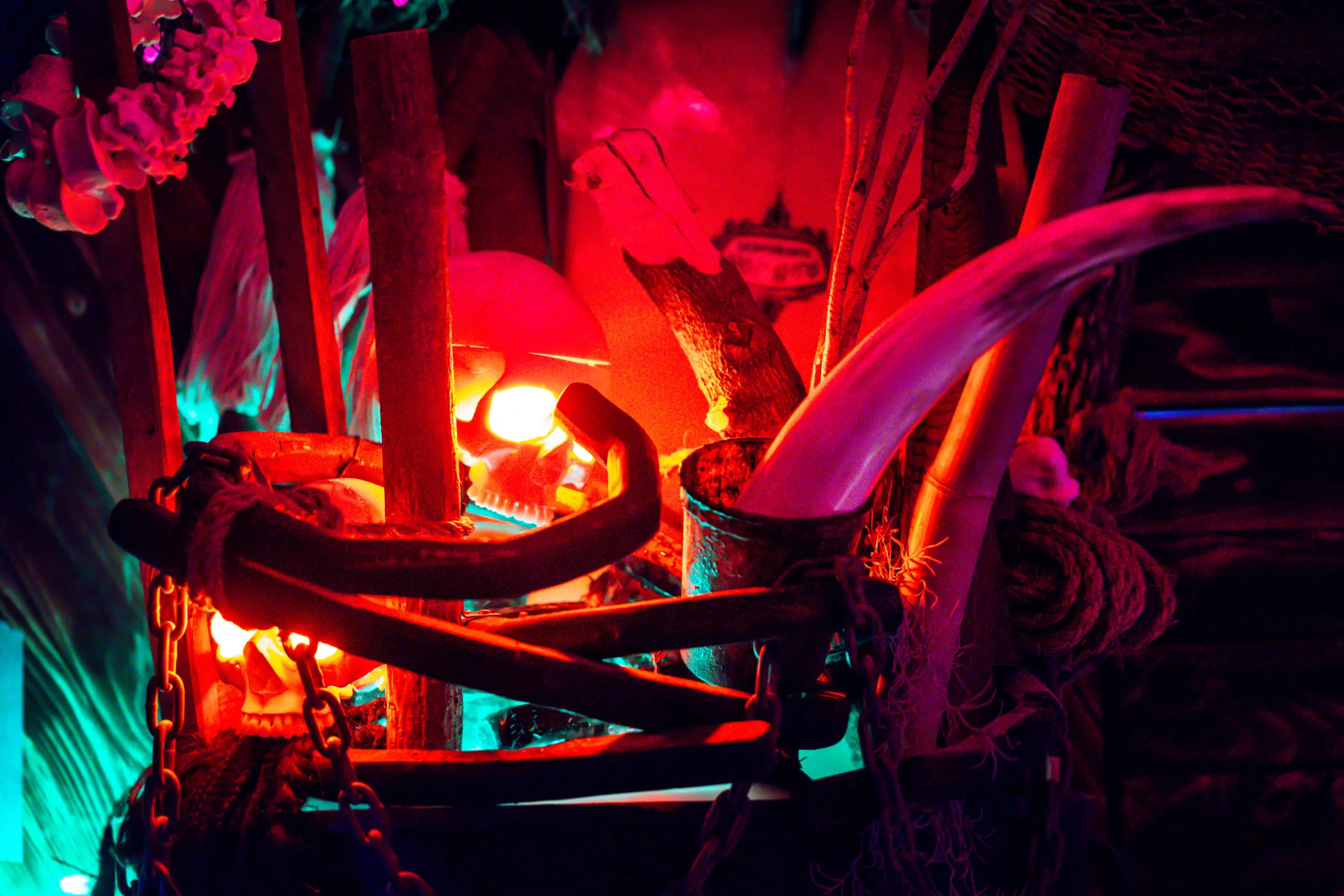 Glowing red lamp among carved wooden forms at Paradise Lost