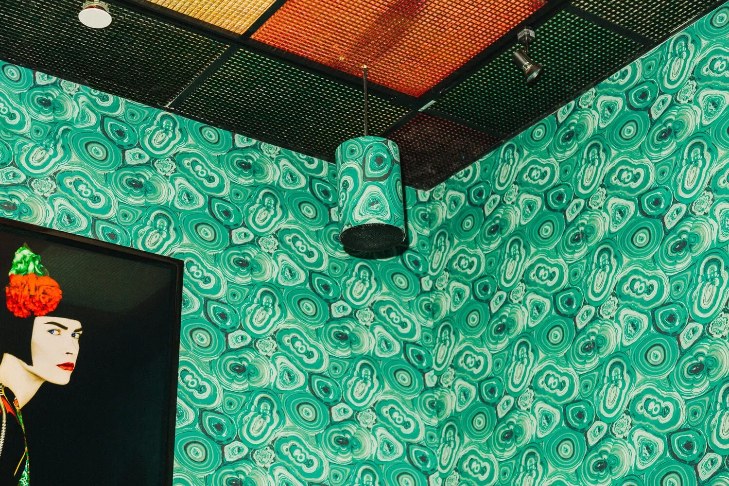 Green patterned room at Turk's Inn with brass lanterns and a framed portrait