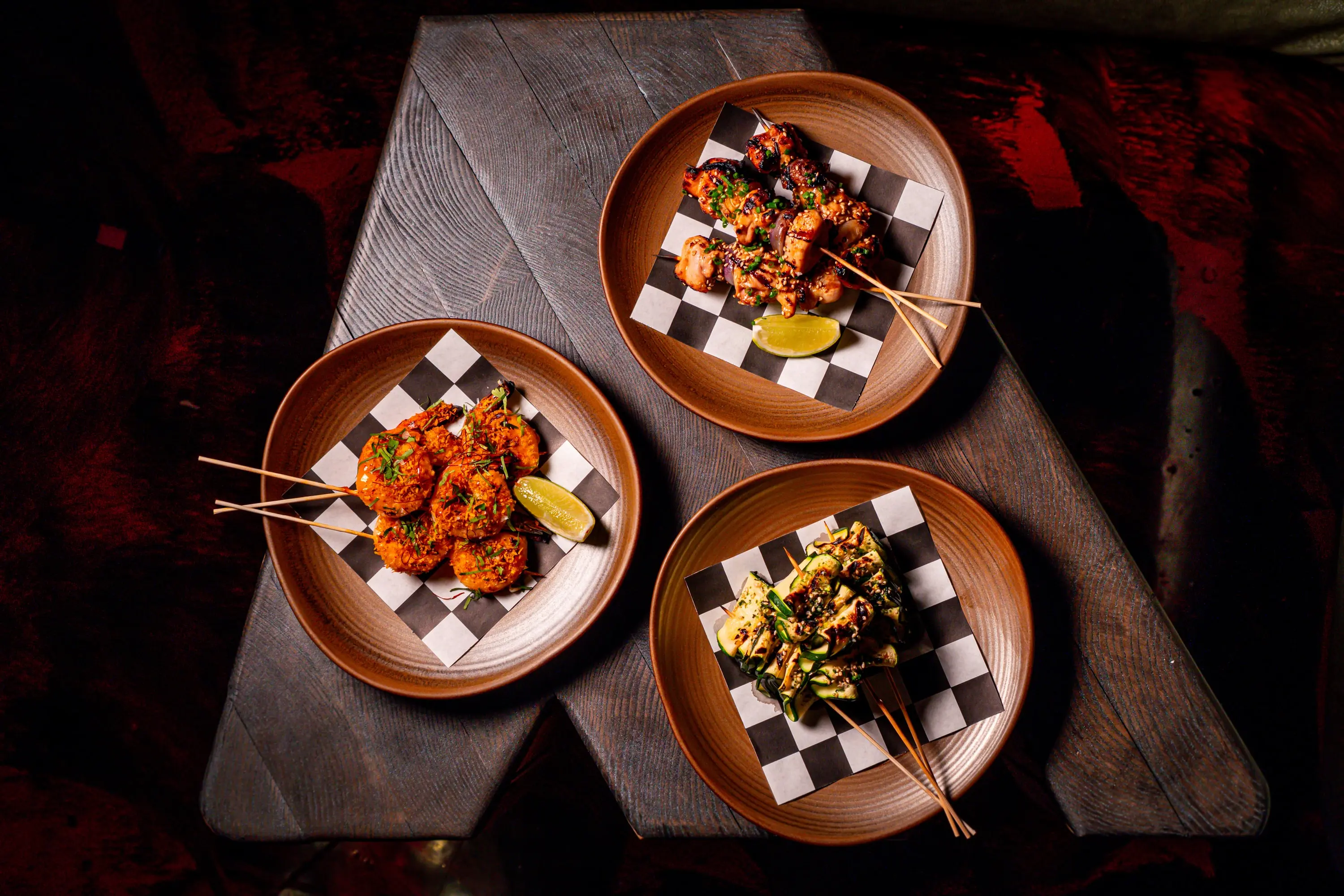 Skewers served on checkerboard plates at Paradise Lost